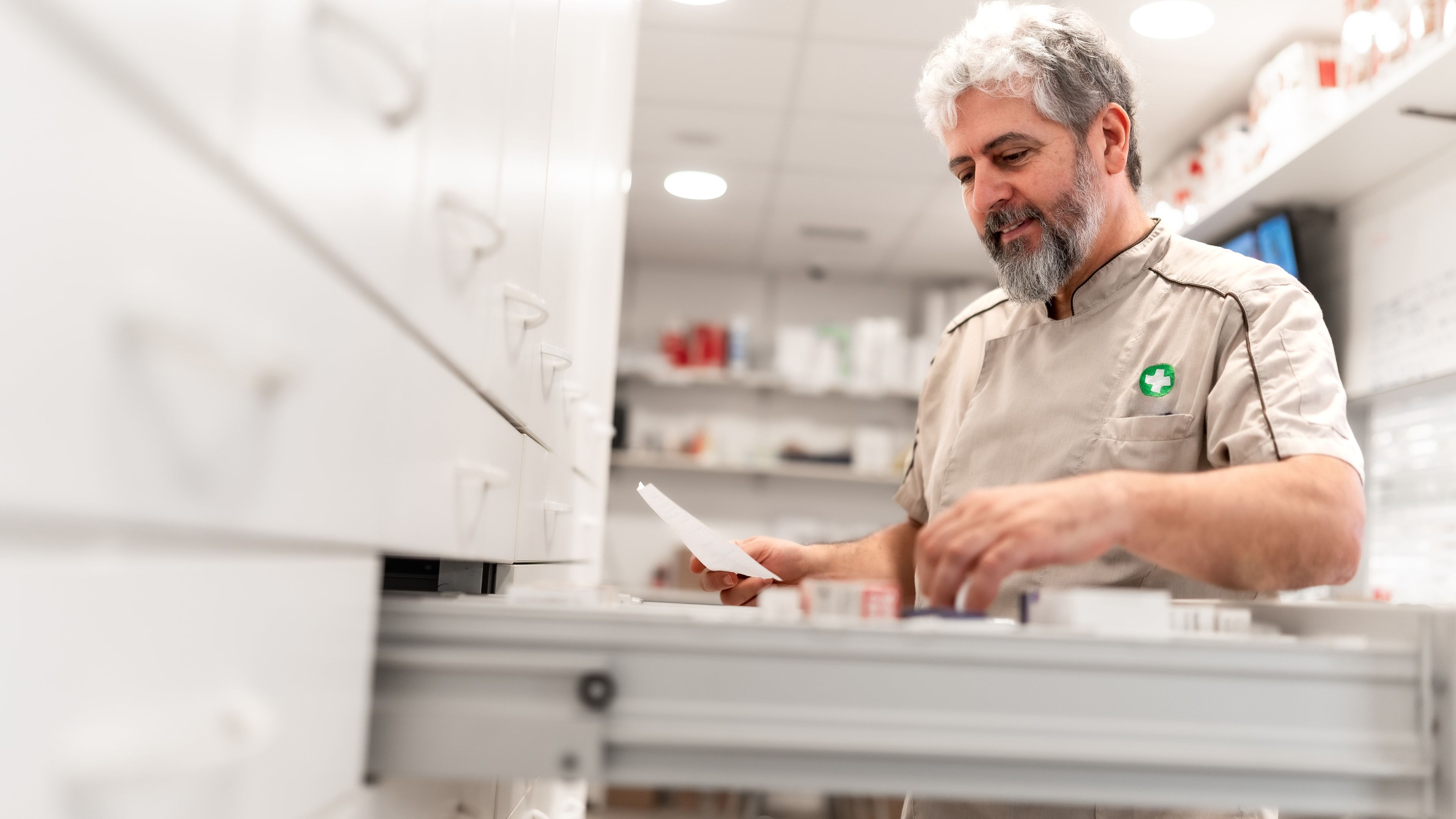 Técnico revisando la referencia de un medicamento en un cajón del almacén farmacéutico
